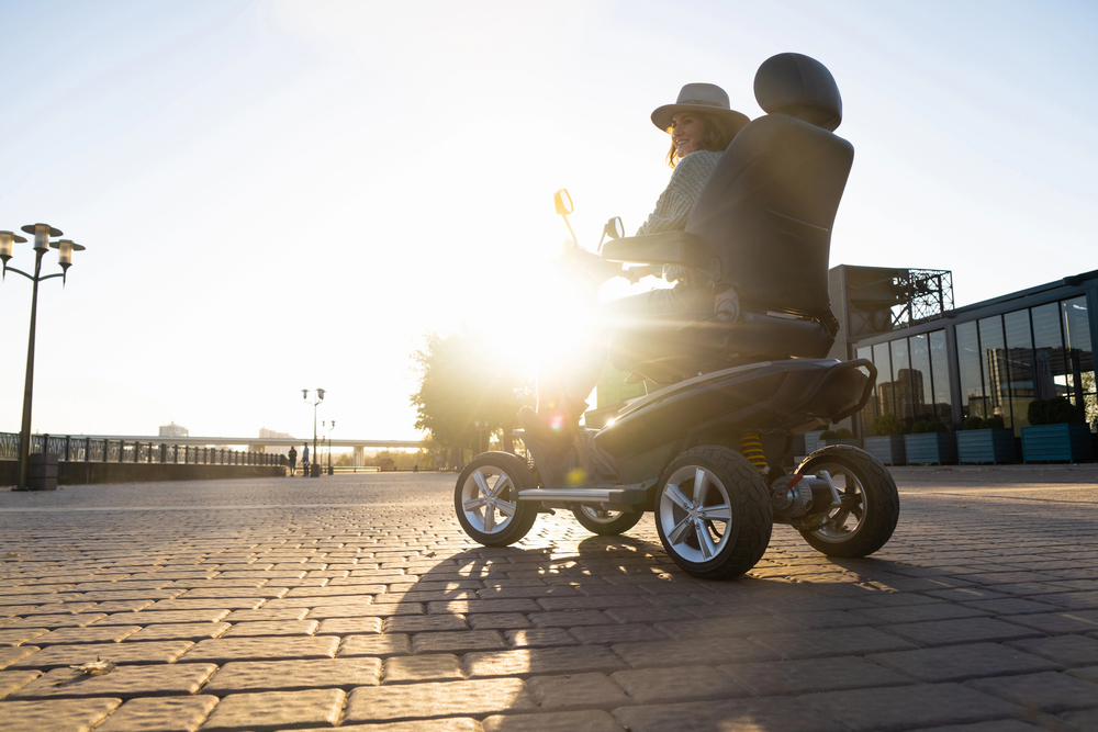 Woman tourist riding a four wheel mobility electric scooter QualiMed standing by with the mobility, lift, and respiratory equipment you need